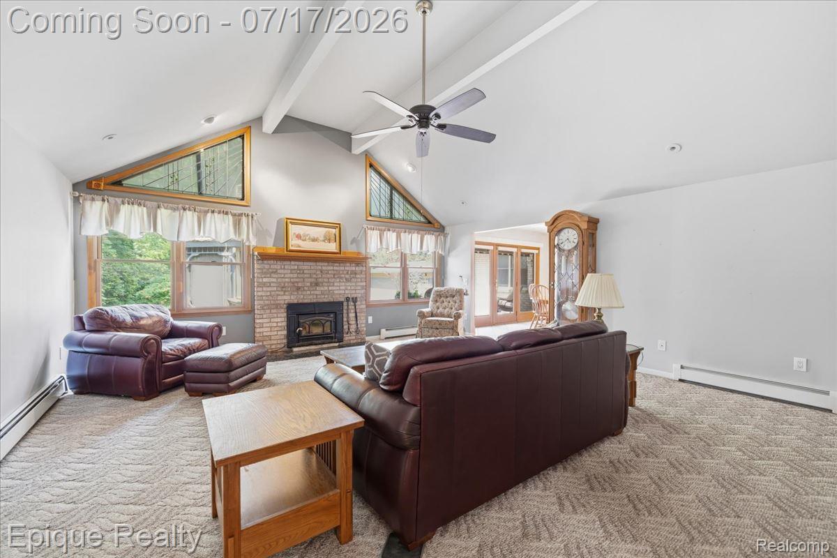 22520 Waltz Road New Boston, MI 48164 - Photo 12 of 43 Vaulted ceiling with exposed beams, brick fireplace with mantel, ceiling fan, and patterned carpeting