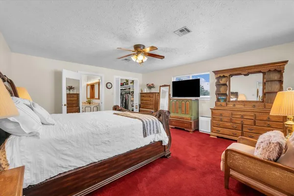 a spacious bedroom with a bed and flat screen tv