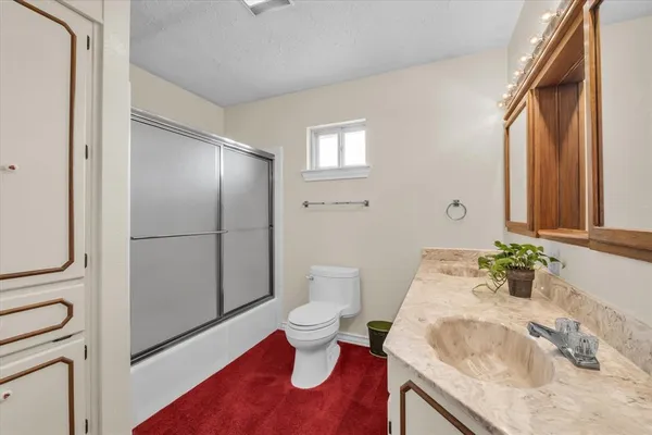 a bathroom with a granite countertop sink toilet and shower