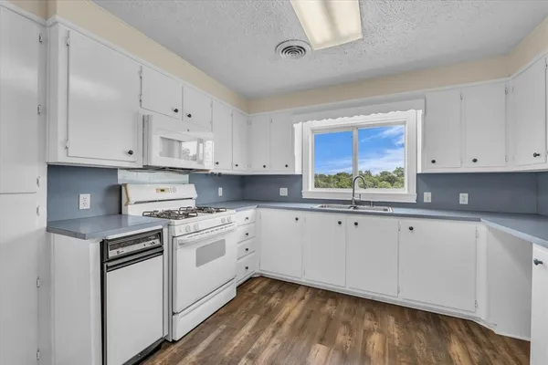 a kitchen with white cabinets stainless steel appliances and a window