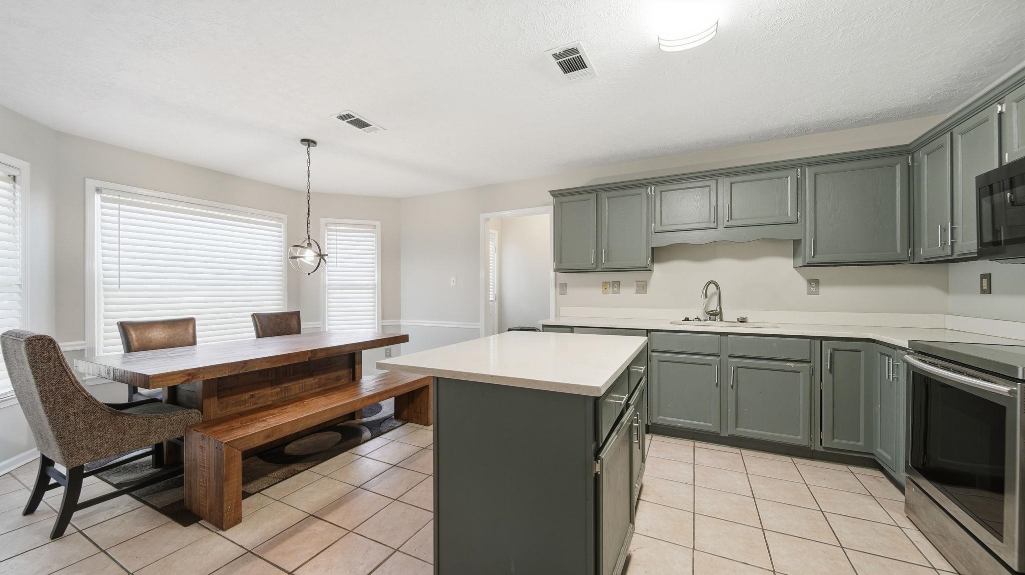 1785 Candle Ridge Drive Cordova, TN 38016 - Photo 13 of 39 Kitchen with electric stove, a center island, pendant lighting, light tile patterned floors, and a textured ceiling