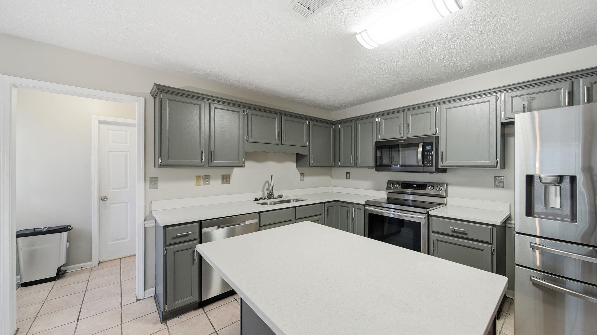 1785 Candle Ridge Drive Cordova, TN 38016 - Photo 17 of 39 Kitchen featuring gray cabinets, appliances with stainless steel finishes, light countertops, light tile patterned floors, and a kitchen island