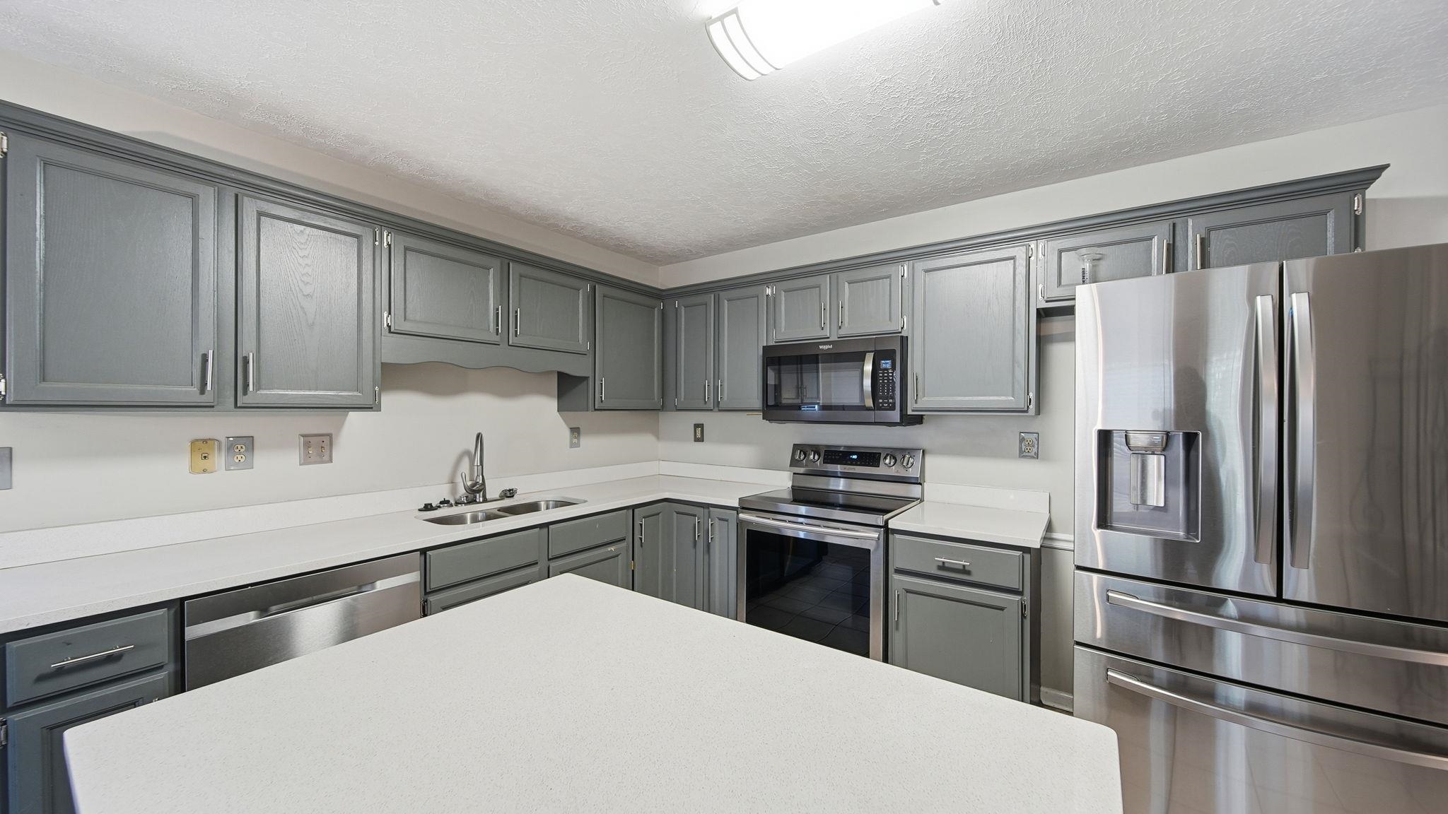 1785 Candle Ridge Drive Cordova, TN 38016 - Photo 21 of 40 a kitchen with stainless steel appliances a sink stove refrigerator and cabinets