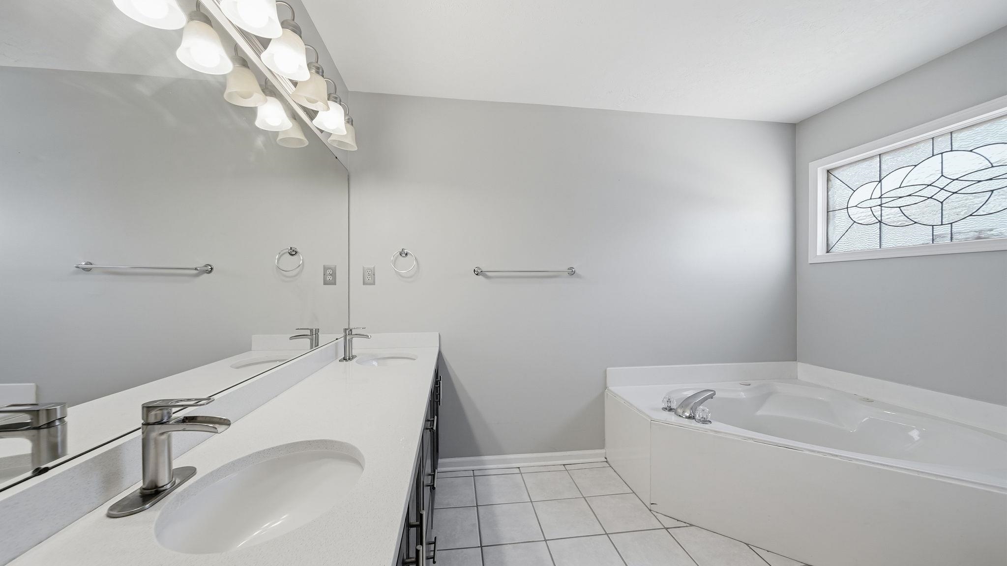 1785 Candle Ridge Drive Cordova, TN 38016 - Photo 25 of 39 Full bath with double vanity, a garden tub, and light tile patterned floors