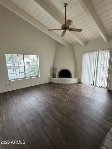 an empty room with wooden floor chandelier ceiling fan and windows