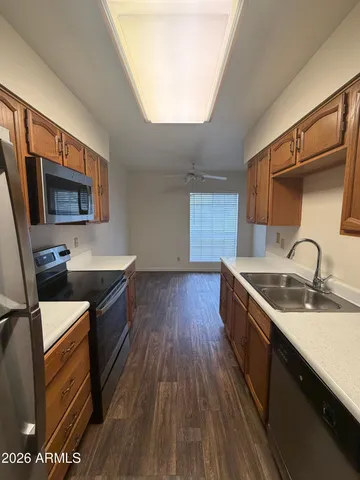 a kitchen with granite countertop a sink wooden floor and stainless steel appliances