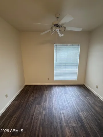 an empty room with wooden floor closet and fan