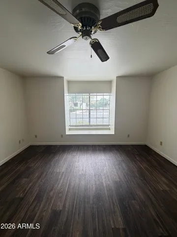 an empty room with wooden floor chandelier and windows