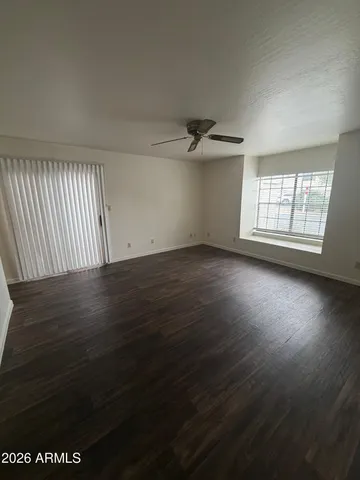 an empty room with wooden floor fan and windows