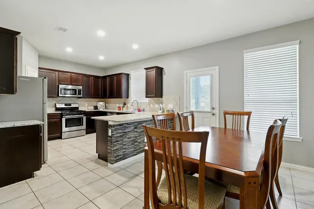 a kitchen with stainless steel appliances granite countertop a stove a sink a microwave a dining table and chairs