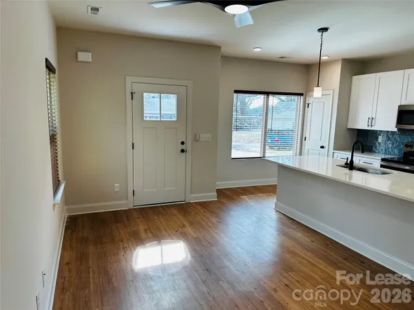 a view of an empty room with window and wooden floor