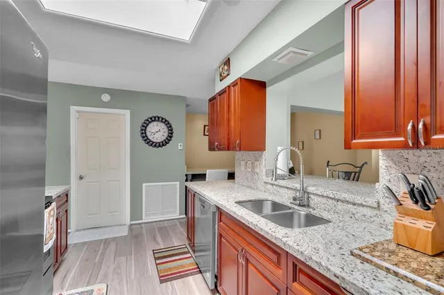 a kitchen with granite countertop a sink a stove and wooden cabinets