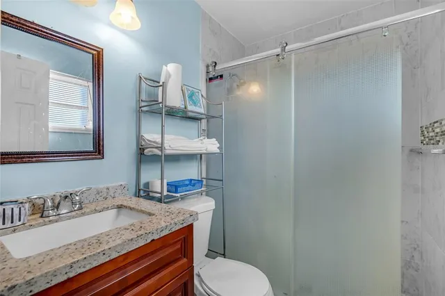 a bathroom with a granite countertop sink toilet and shower