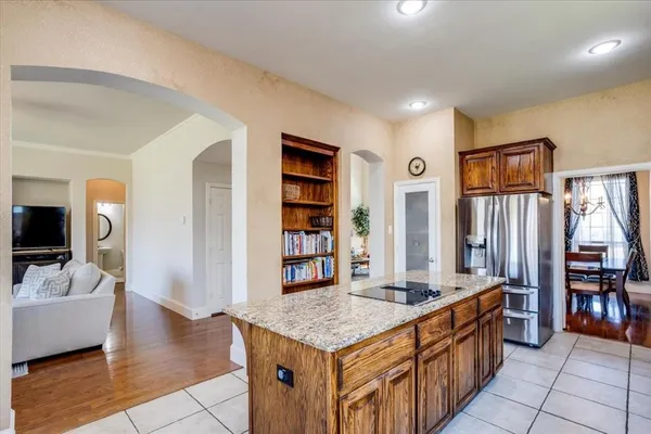 a living room with stainless steel appliances kitchen island granite countertop a table chairs and a large window
