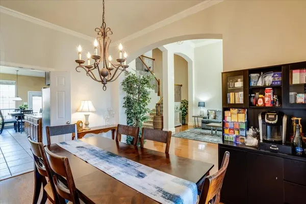 a dining room with wooden floor a chandelier a wooden table and chairs