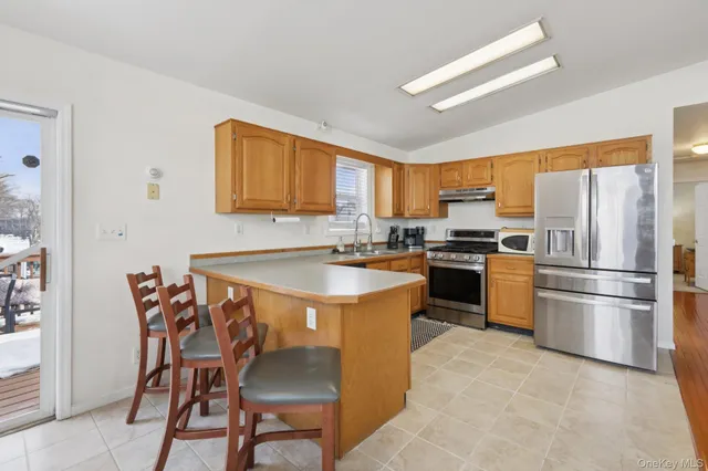 a kitchen with stainless steel appliances granite countertop a stove a refrigerator a sink a dining table and chairs with wooden floor