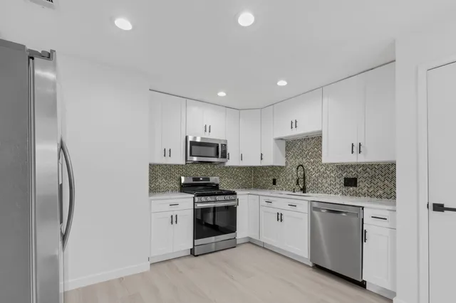 a kitchen with white cabinets and stainless steel appliances