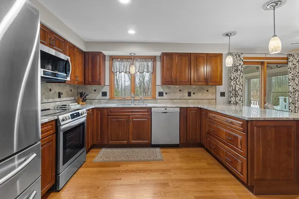 a kitchen with stainless steel appliances granite countertop a sink a stove a refrigerator cabinets and a window