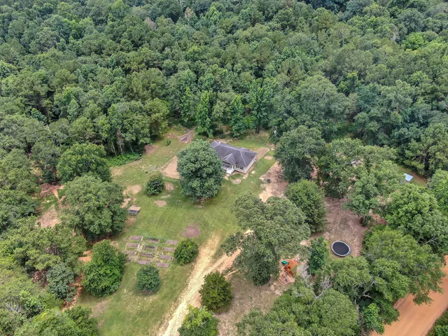an aerial view of residential house with outdoor space and trees all around