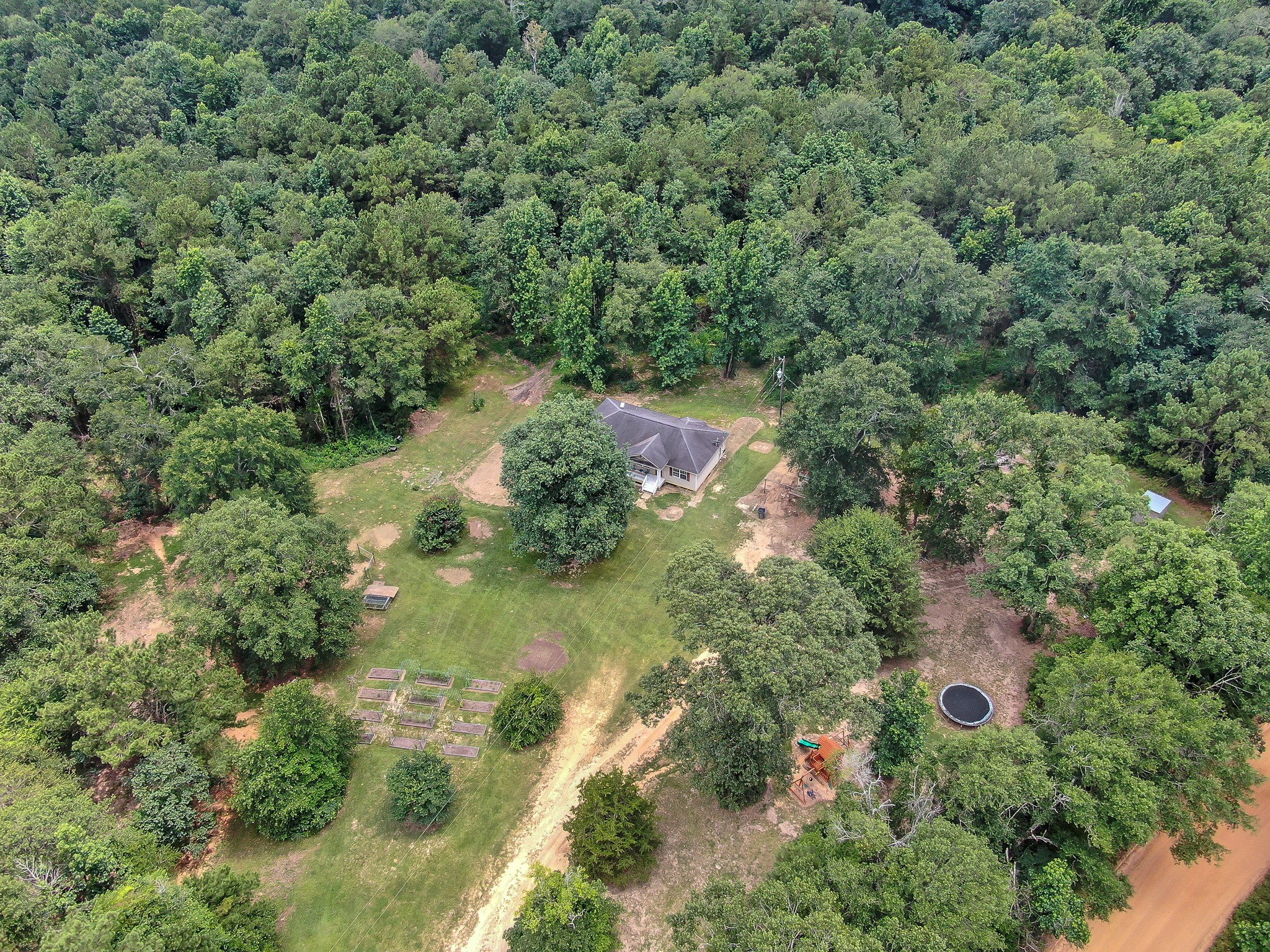 an aerial view of residential house with outdoor space and trees all around