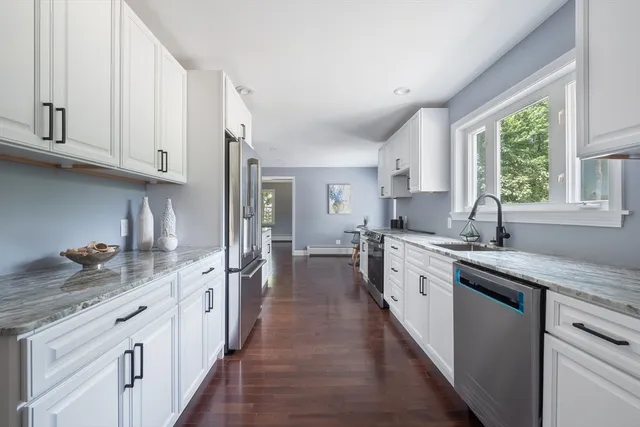 a kitchen with granite countertop a sink stove refrigerator and cabinets