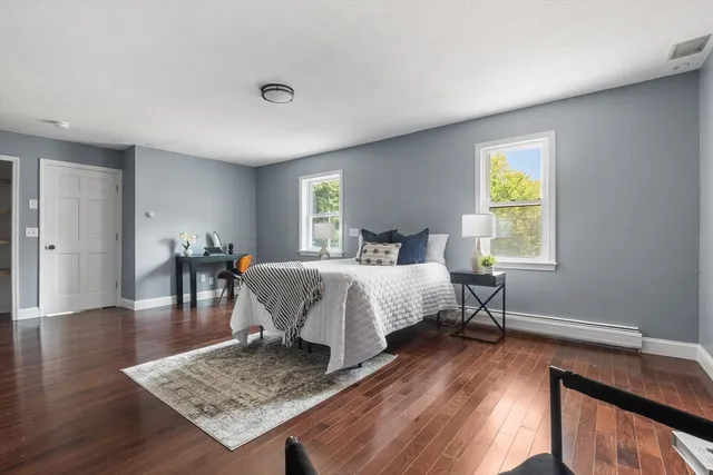 a bedroom with a bed a table and wooden floor