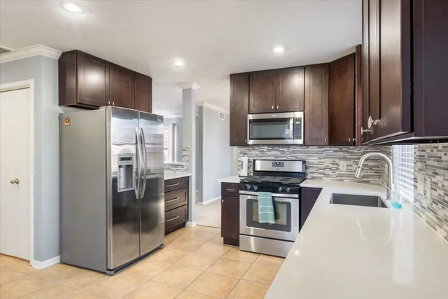 a large kitchen with stainless steel appliances kitchen island granite countertop a stove refrigerator and cabinets