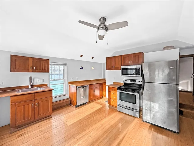 a kitchen with stainless steel appliances a stove refrigerator sink and wooden floor