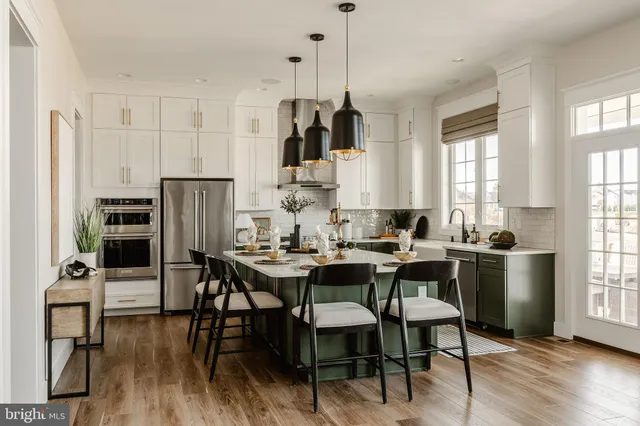 a kitchen with stainless steel appliances kitchen island granite countertop a table chairs and a refrigerator
