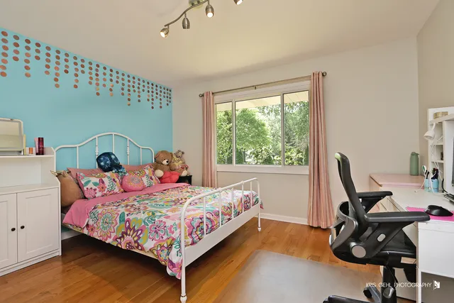 a bedroom with a bed chair and wooden floor