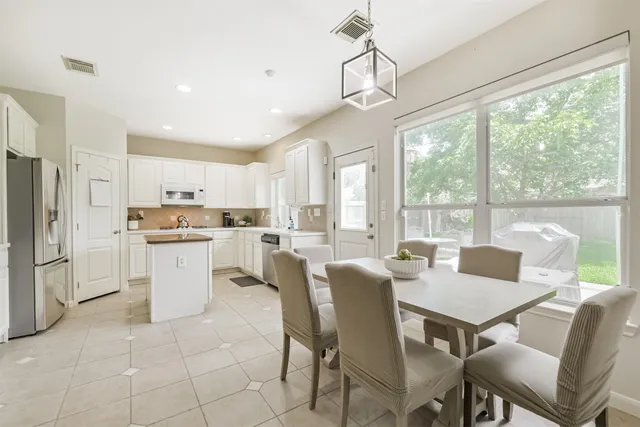 a open dining room with stainless steel appliances granite countertop a stove a kitchen island a table and chairs