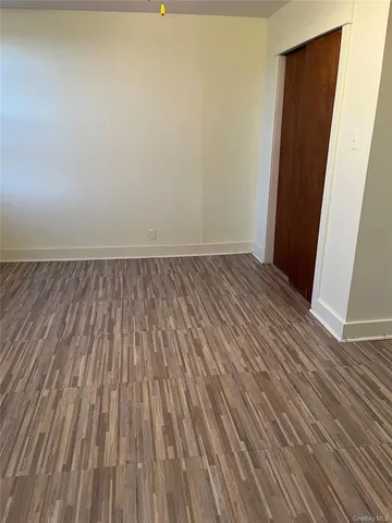 a view of an empty room with wooden floor and a wall painting