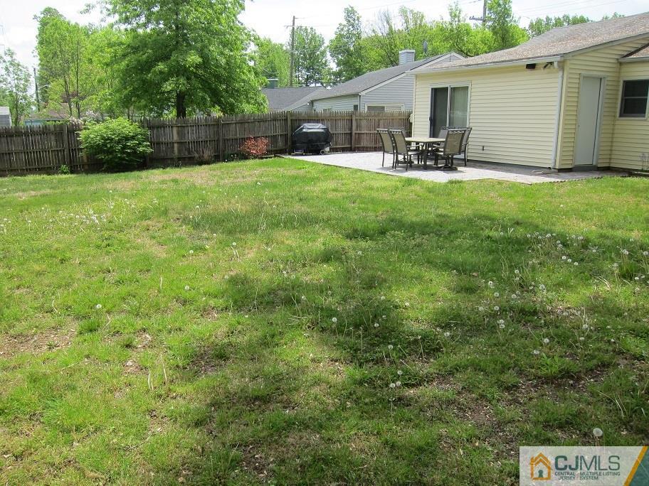 41 Colton Road Edison, NJ 08817 - Photo 14 of 16 a view of a backyard with table and chairs potted plants and wooden fence