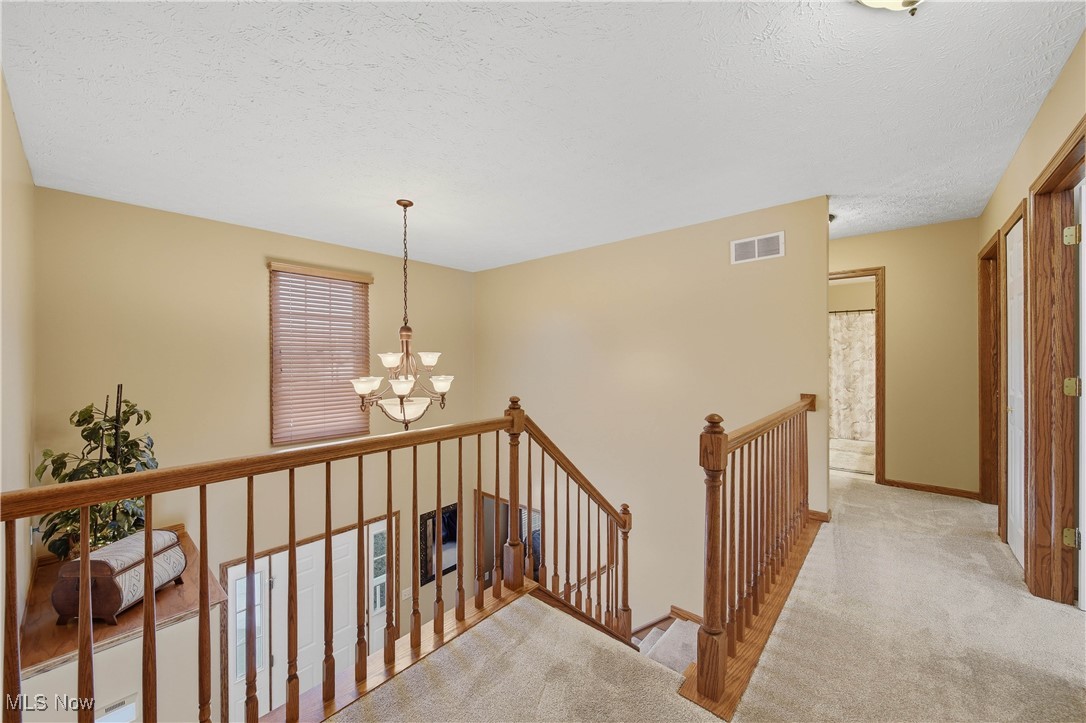 2132 Summerchase Road Northeast Canton, OH 44721 - Photo 21 of 49 Corridor featuring an upstairs landing, carpet floors, a chandelier, and a textured ceiling