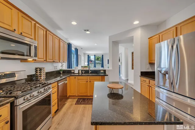 a large kitchen with stainless steel appliances granite countertop a stove a sink and a refrigerator