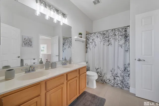 a spacious bathroom with a double vanity sink toilet and a mirror