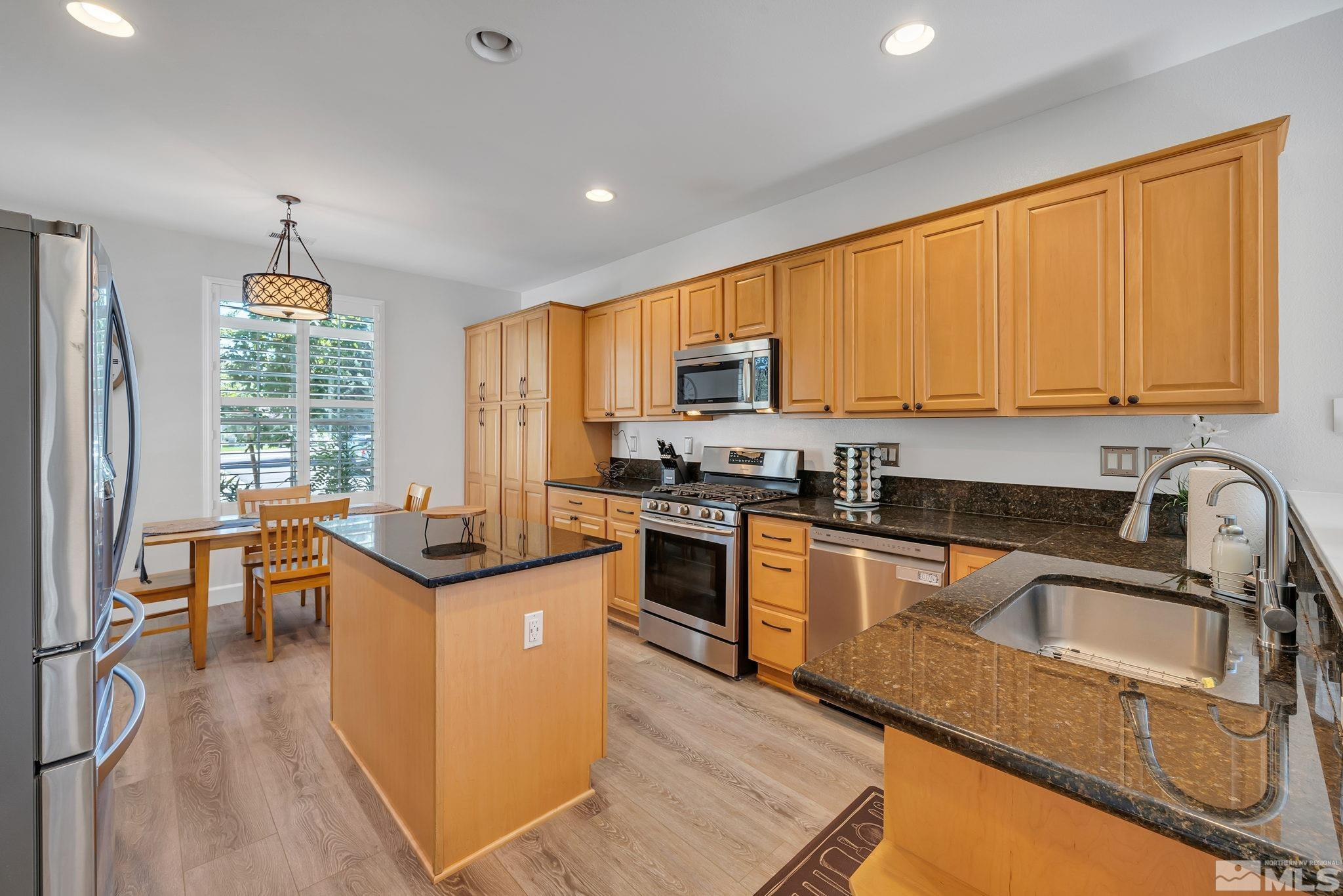 10459 Summershade Lane Reno, NV 89521 - Photo 10 of 37 a kitchen with stainless steel appliances granite countertop a stove top oven a sink dishwasher a dining table and chairs with wooden floor