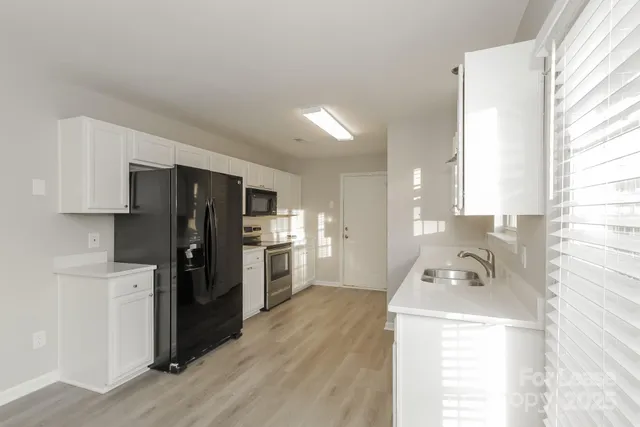 a kitchen with a refrigerator a stove top oven and a window