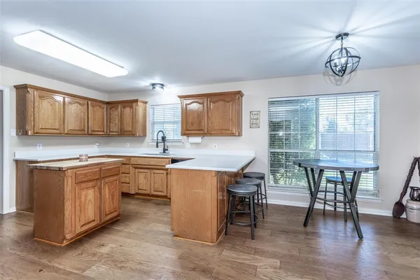 a kitchen with stainless steel appliances granite countertop a stove top oven a sink dishwasher a dining table and chairs with wooden floor