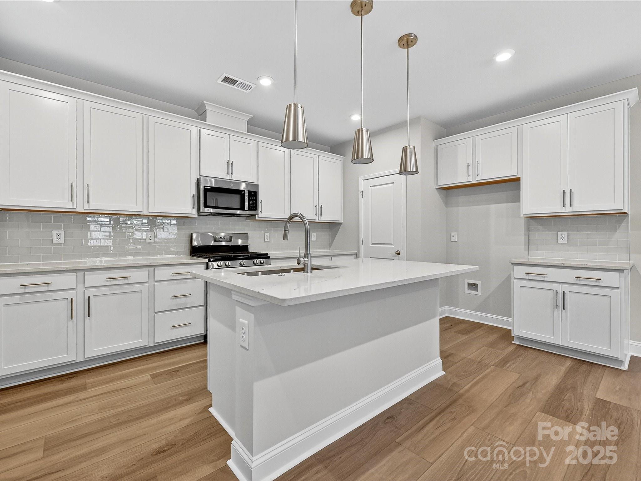 489 Nash Street Fort Mill, SC 29715 - Photo 7 of 24 a kitchen with kitchen island white cabinets appliances and a sink