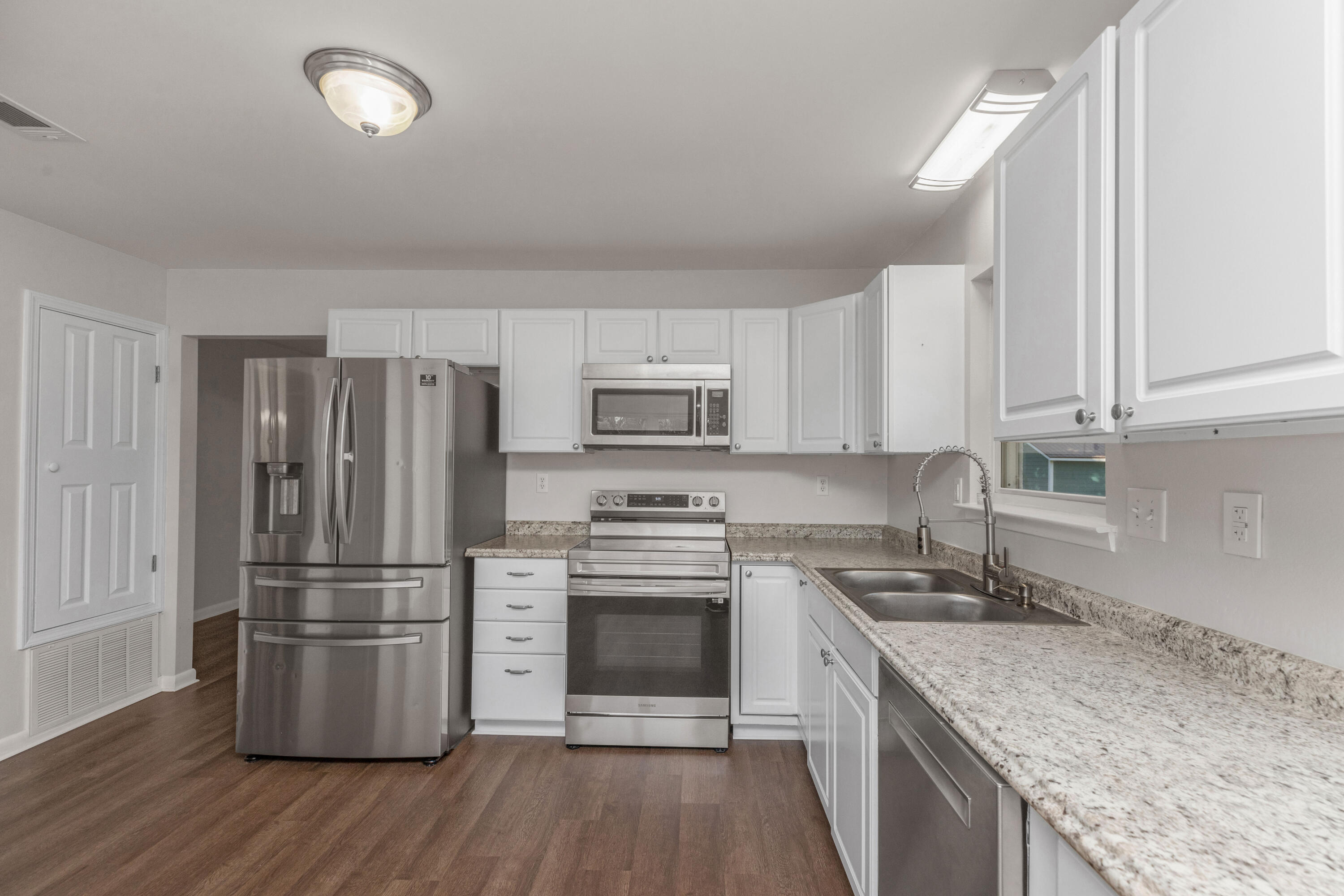 229 Madison Street Freeport, FL 32439 - Photo 13 of 44 a kitchen with granite countertop white cabinets and stainless steel appliances
