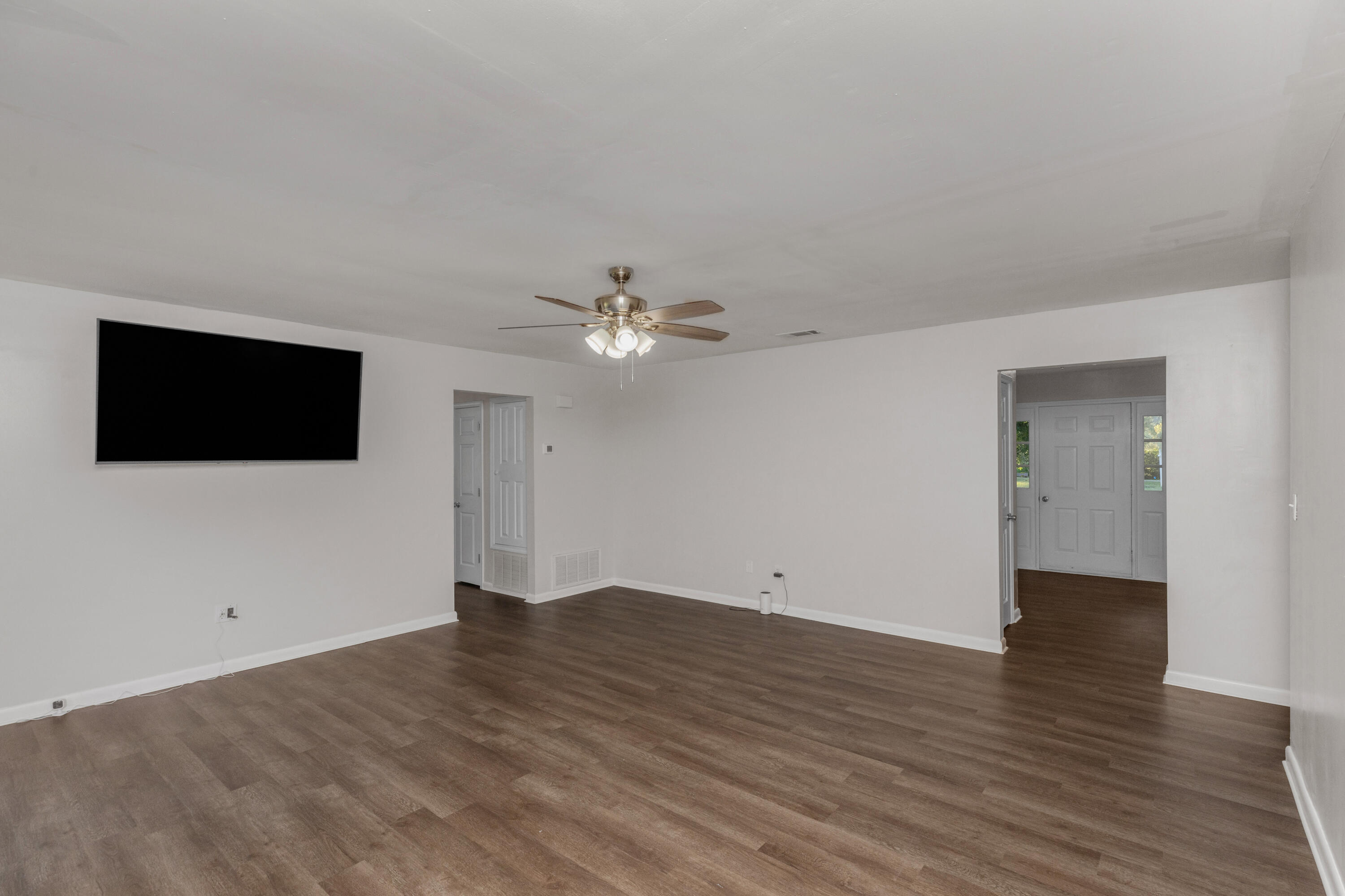 229 Madison Street Freeport, FL 32439 - Photo 19 of 44 a view of an empty room with wooden floor and fan