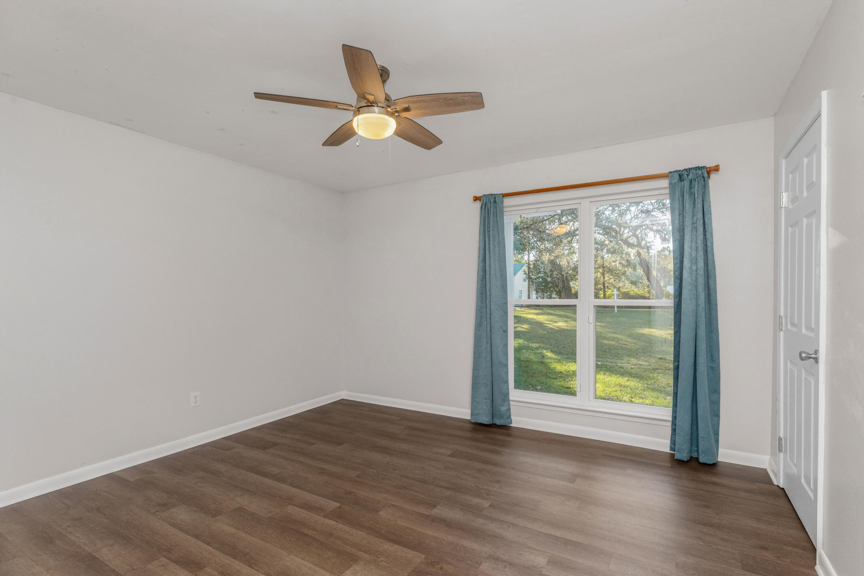 229 Madison Street Freeport, FL 32439 - Photo 21 of 44 a view of an empty room with wooden floor and a window