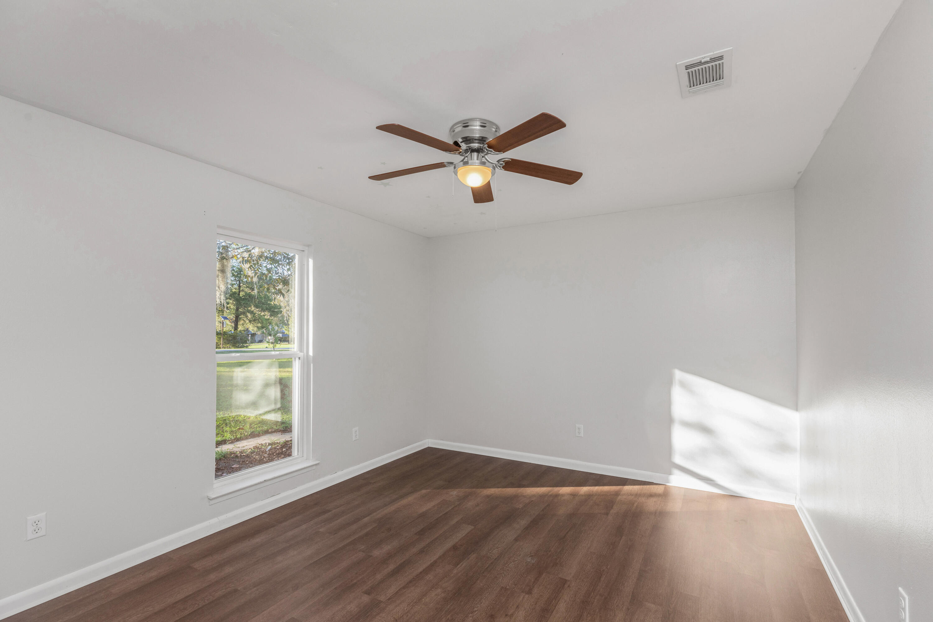 229 Madison Street Freeport, FL 32439 - Photo 23 of 44 wooden floor in an empty room with a window
