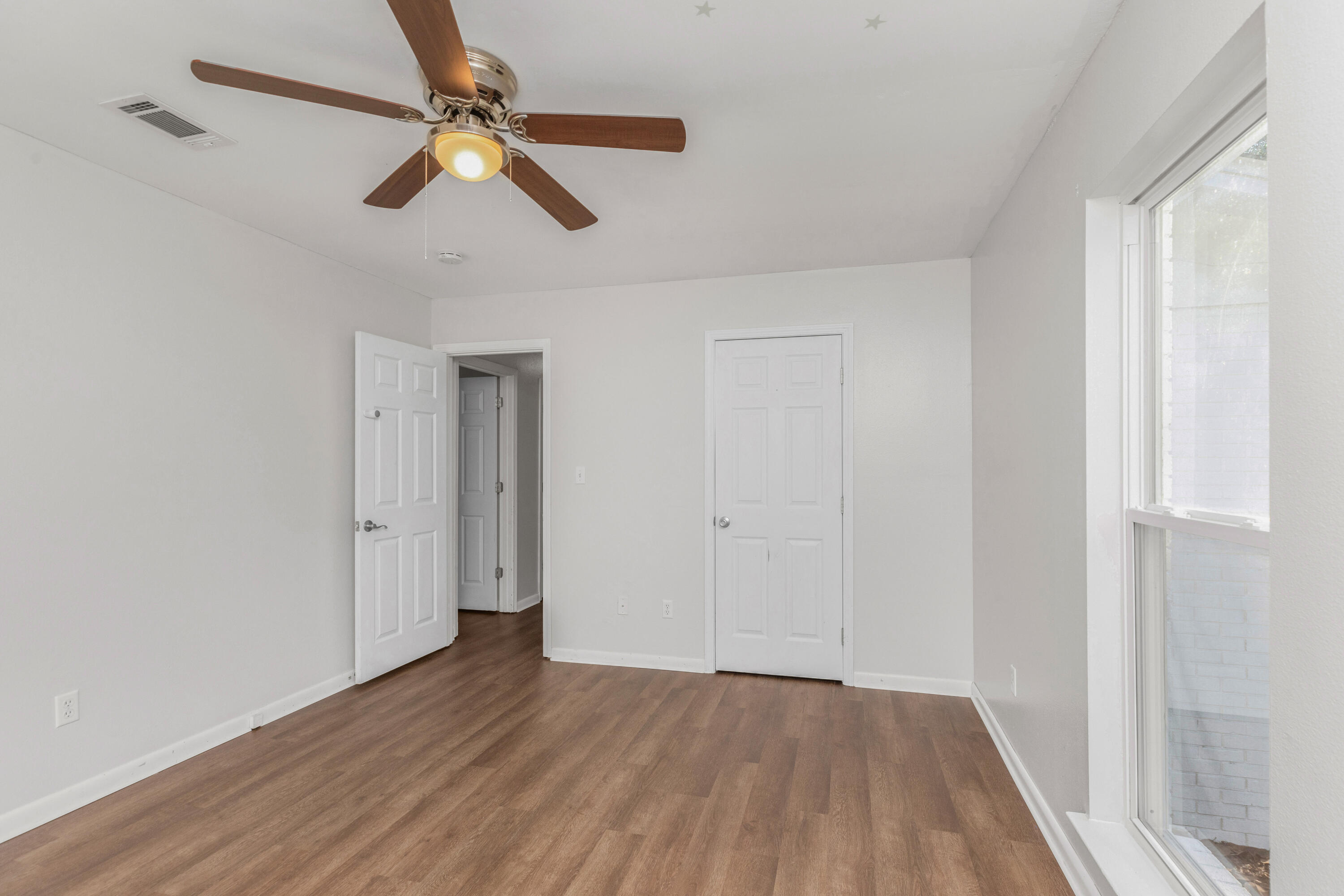 229 Madison Street Freeport, FL 32439 - Photo 25 of 44 an empty room with wooden floor ceiling fan and windows