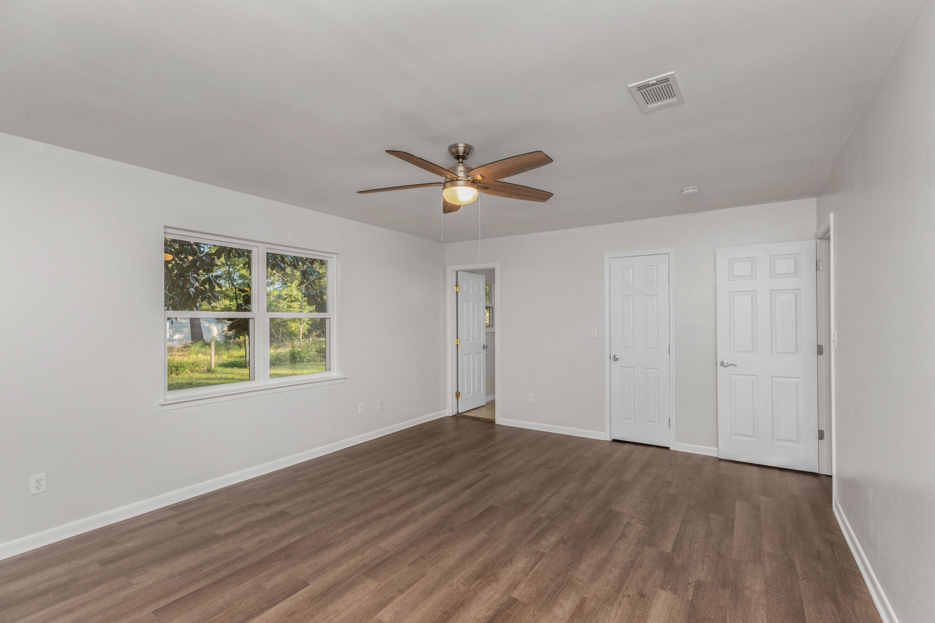 229 Madison Street Freeport, FL 32439 - Photo 29 of 44 a view of an empty room with wooden floor and a ceiling fan