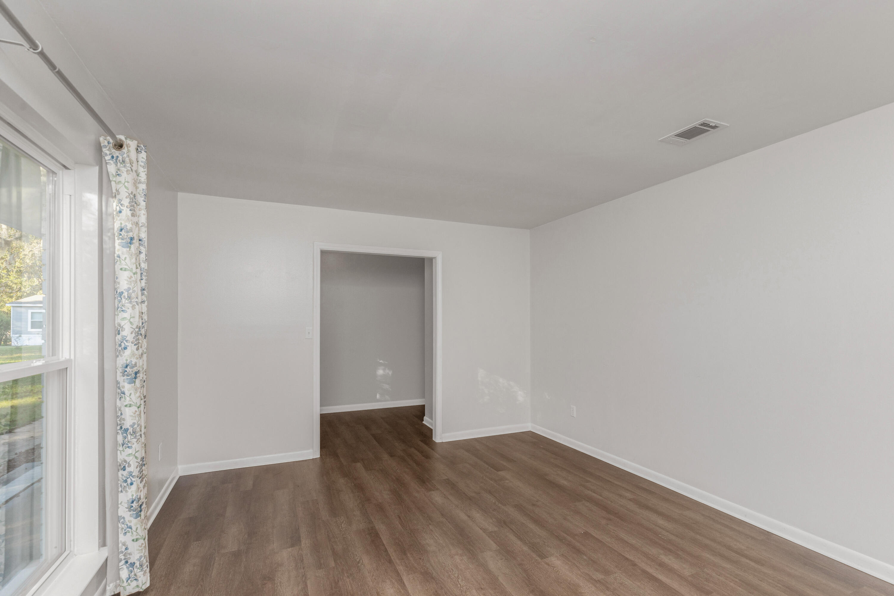 229 Madison Street Freeport, FL 32439 - Photo 8 of 44 a view of an empty room with wooden floor and a window