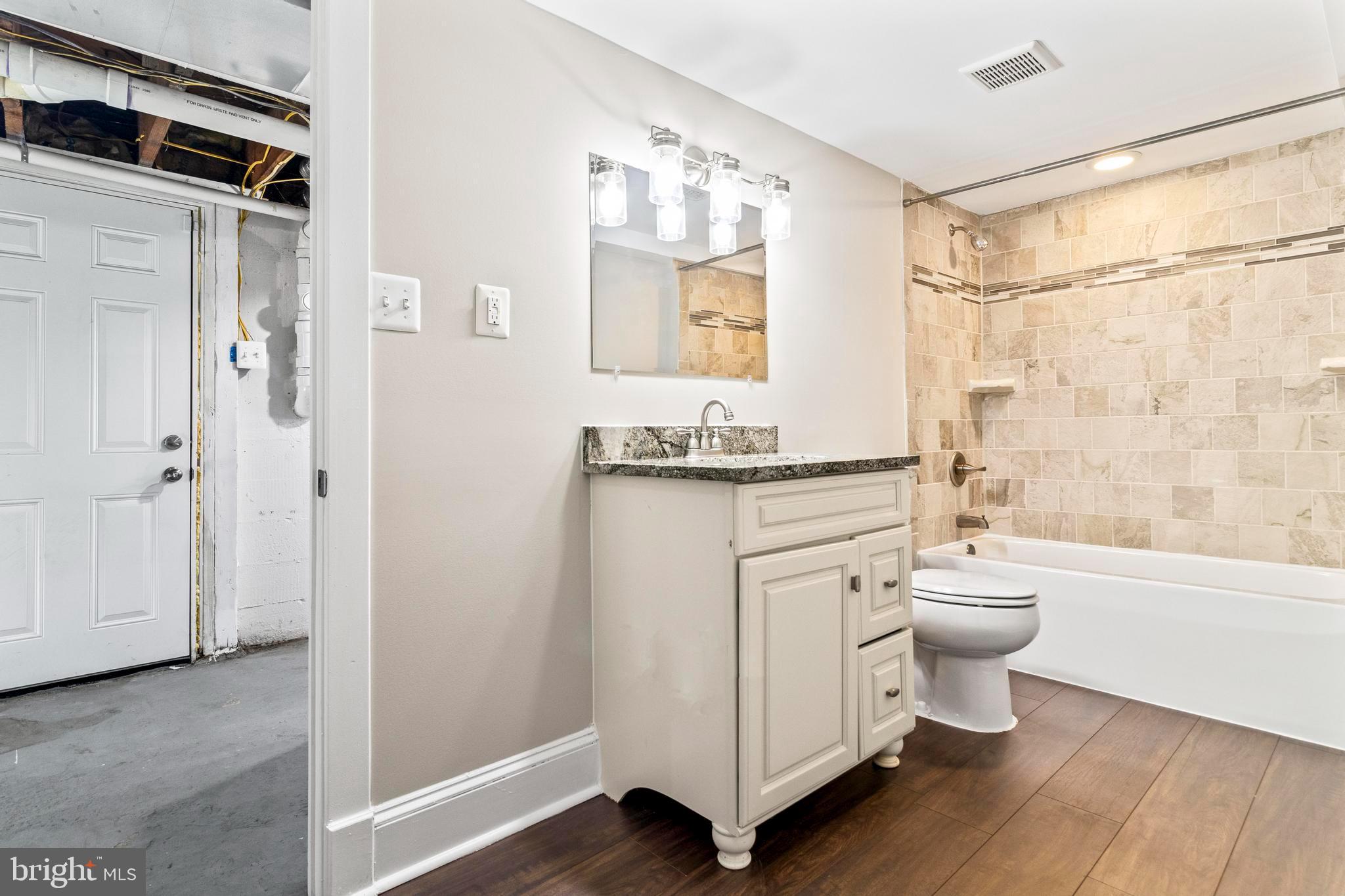 9005 Fairground Road Bel Alton, MD 20611 - Photo 33 of 54 a bathroom with a granite countertop toilet a sink and a mirror