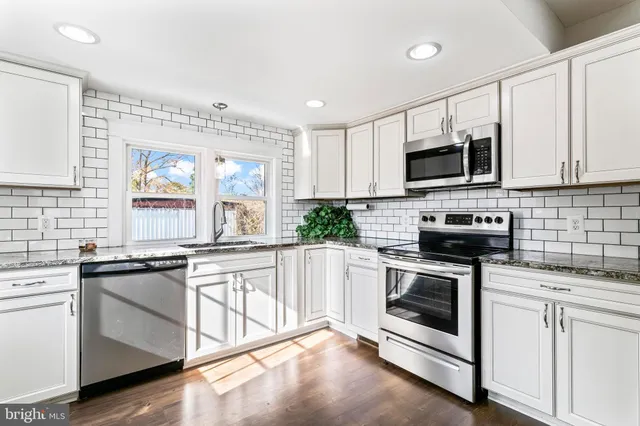 a kitchen with granite countertop white cabinets white stainless steel appliances and a sink