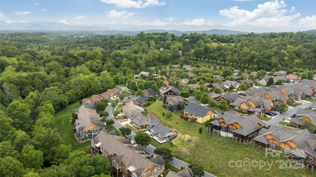 an aerial view of residential houses with outdoor space and trees